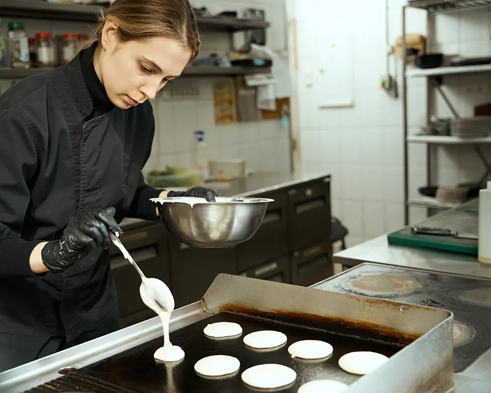 Female chef preparing breakfast — assisted living food service and kitchen food safety
